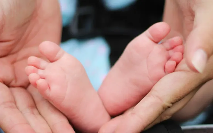 A parent’s hands holding a baby’s feet, for baby-care and mother-care brands
