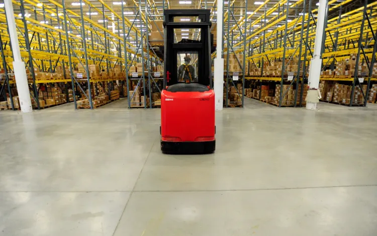 Warehouse aisle with tall pallet racks and a forklift, for industrial and logistics companies
