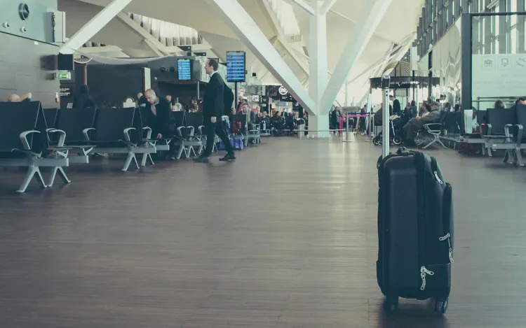 A black suitcase standing in an airport terminal, for travel retailers and luggage brands