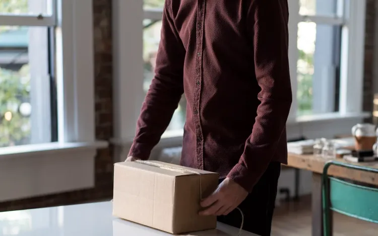 Private label pocket scales for online sellers and d2c brands A man tying up a parcel on a packing table, for online sellers and D2C brands