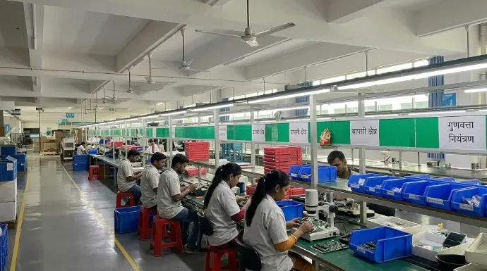 Workers assembling weighing scales along a high-volume production line with quality checkpoints.