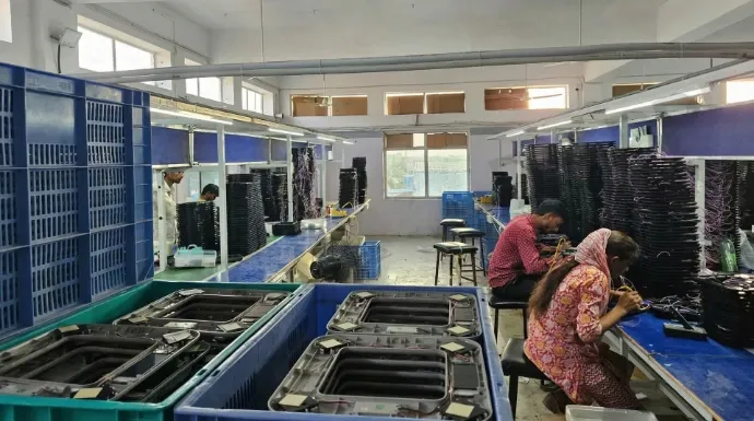 Technicians hand-wiring and assembling PCB components for weighing scales on the factory floor.